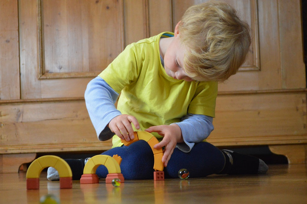 Kind spielt mit Murmeln an kaju-B&ouml;gen